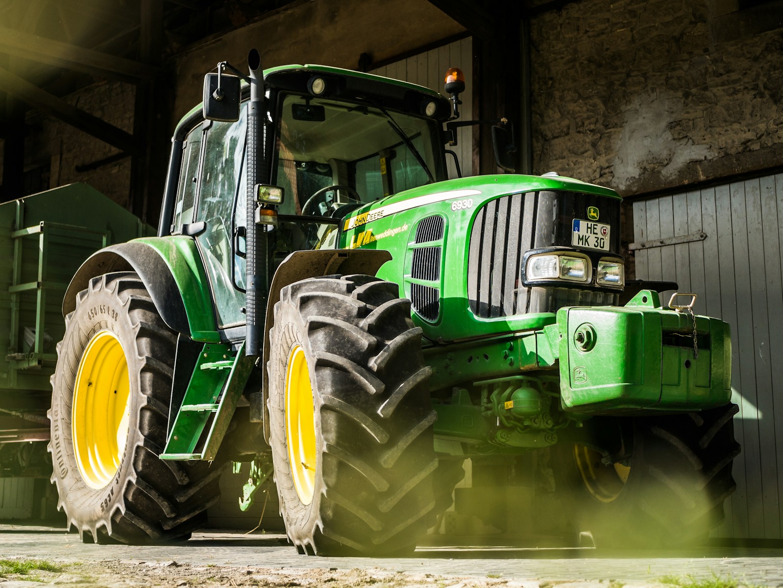 green and yellow tractor with farm equipment coverage in garage