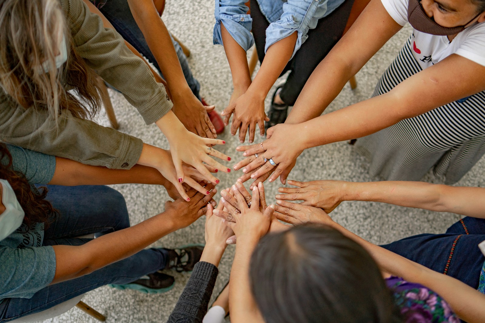 A group of people standing in a circle with their hands together symbolizing nonprofit organizations