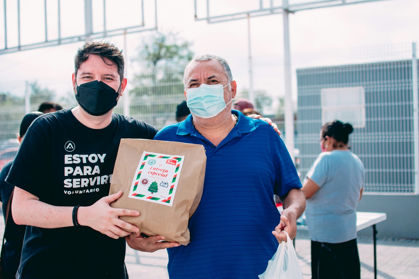 two men wearing masks and holding a bag of food from nonprofits