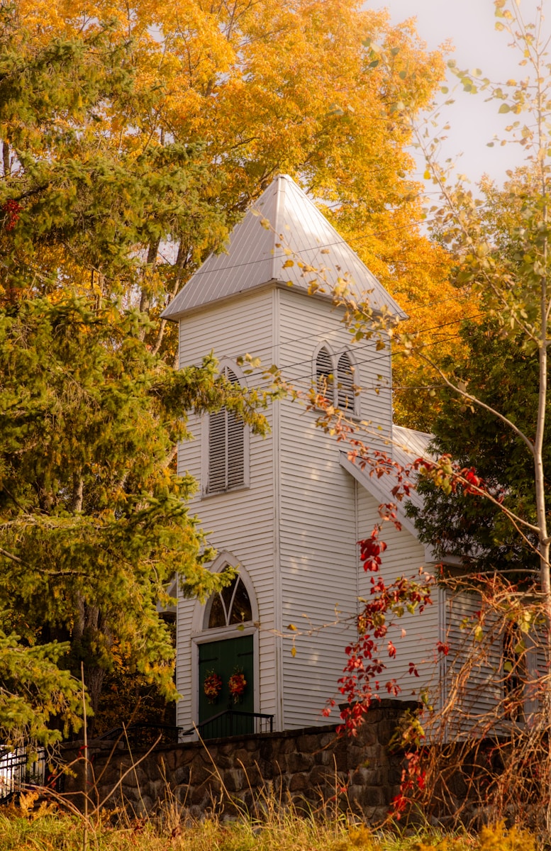 A white church surrounded by trees in the fall